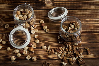 Hazelnuts and Walnuts in Glass Jars on Rustic Wooden Table