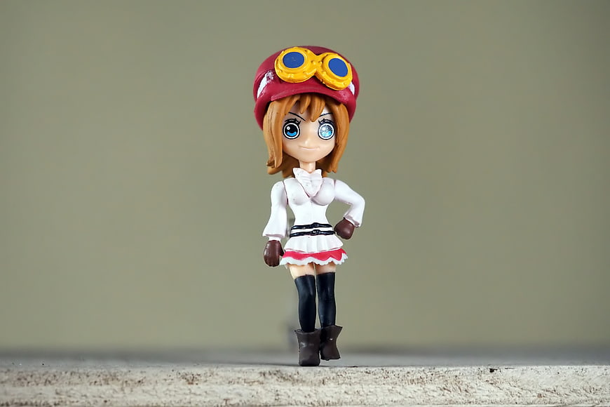 Anime Girl Figurine Wearing Red Cap and Goggles on Neutral Background
