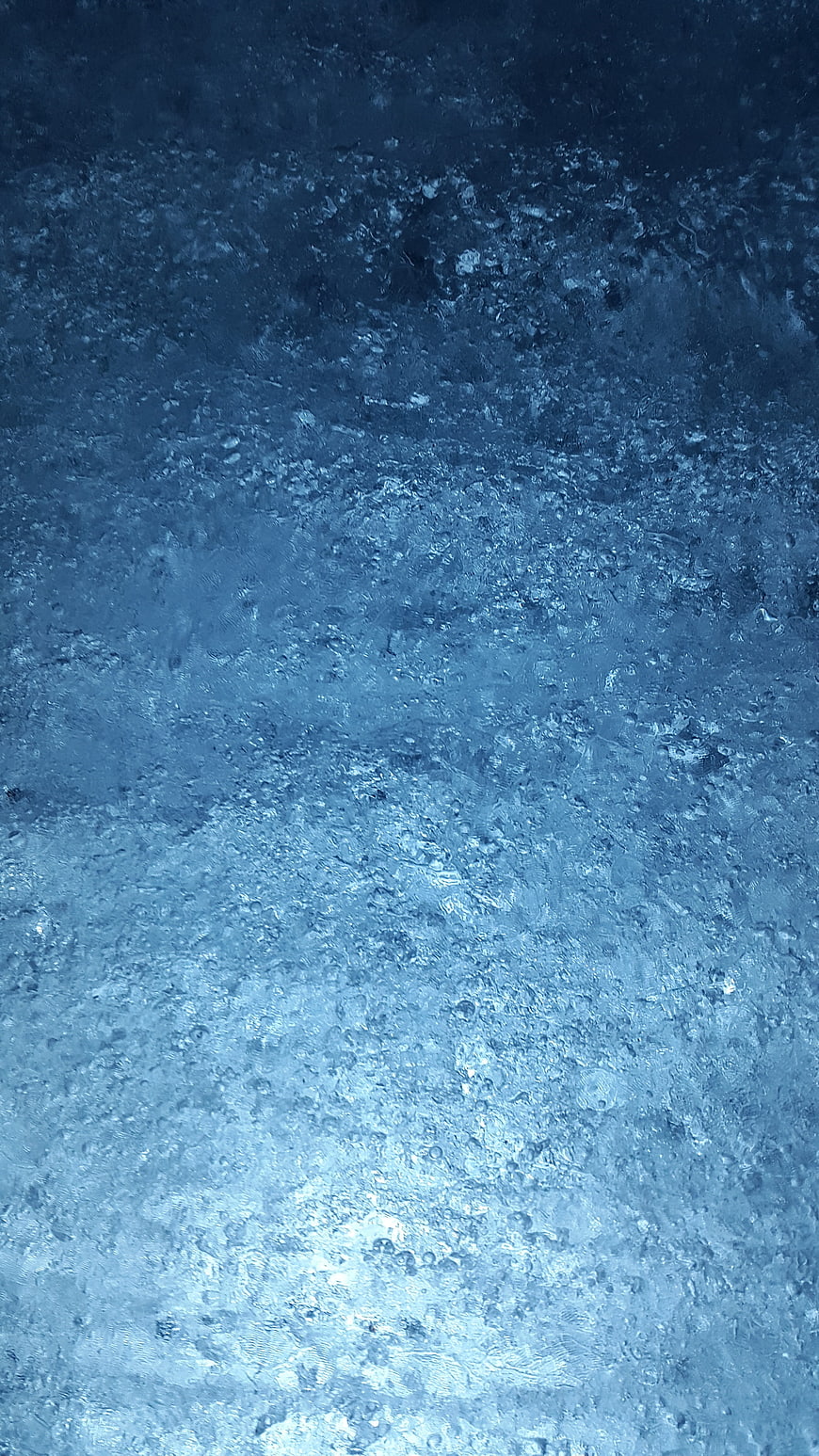 Abstract blue ice texture with frozen bubbles and crystalline structure
