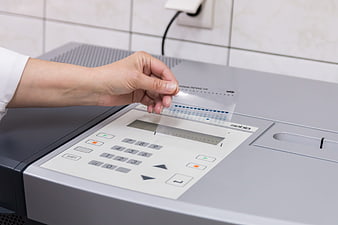 Medical professional inserting diagnostic test strip into laboratory analyzer