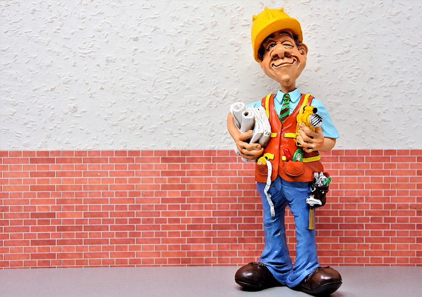 Construction worker figurine with blueprints and tools