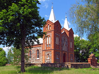 Red Brick Church with Twin Spires in Green Landscape