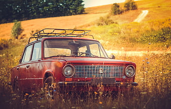 Vintage red car parked in a golden autumn field