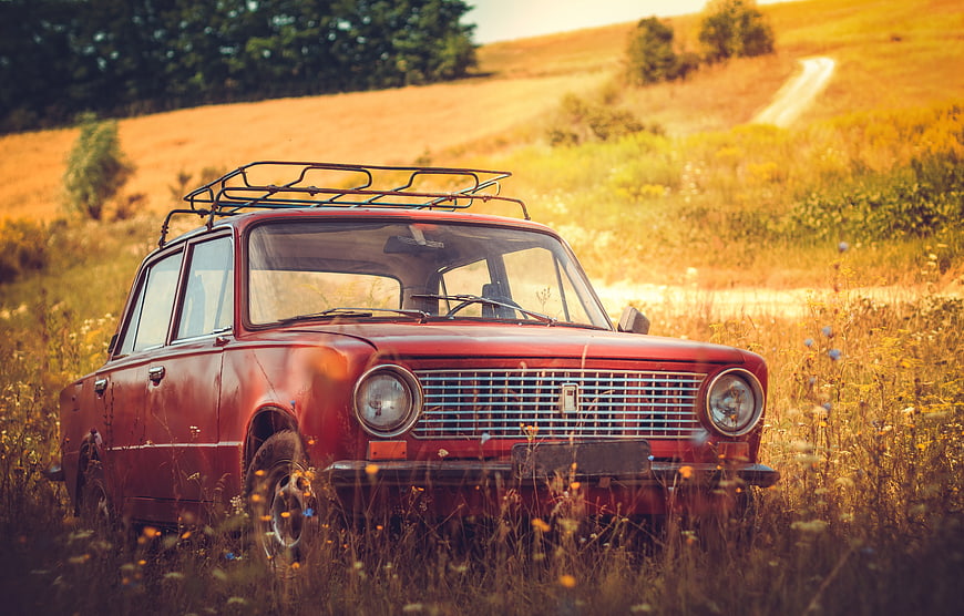 Vintage red car parked in a golden autumn field
