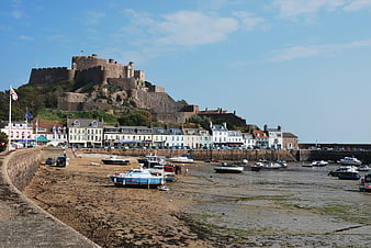 Bamburgh Castle overlooking harbor with boats at low tide
