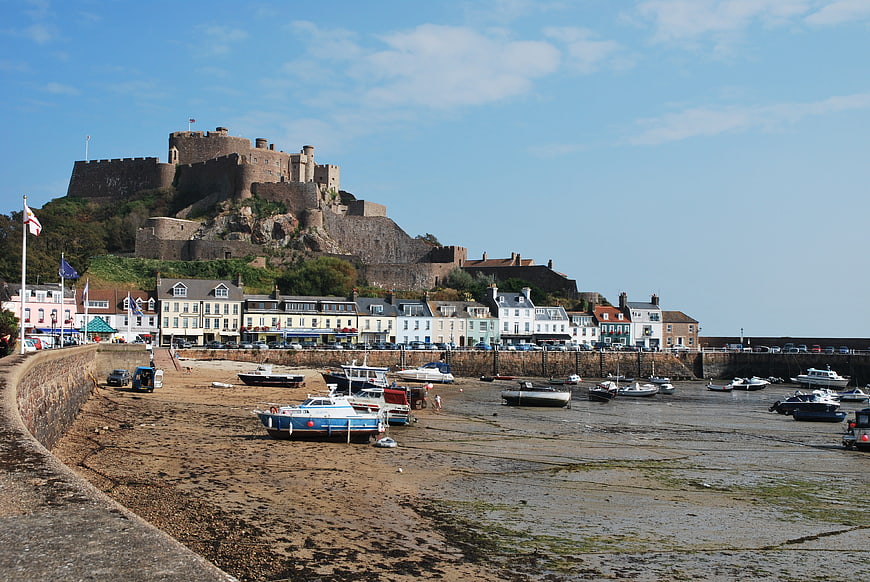 Bamburgh Castle overlooking harbor with boats at low tide