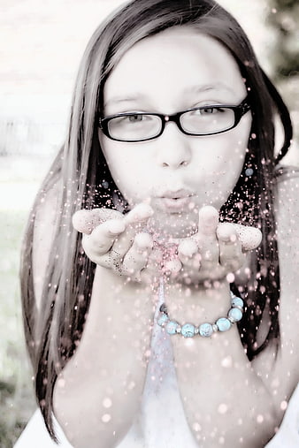 Teenage girl blowing pink glitter with glasses