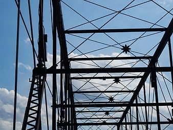 Silhouette of bridge truss structure against blue sky