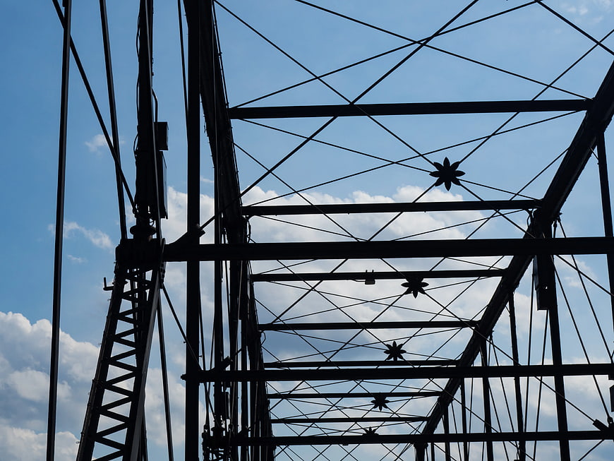Silhouette of bridge truss structure against blue sky