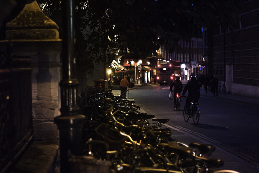 Night street scene with parked bicycles and cyclists in city