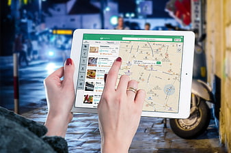 Hands using tablet app to find restaurants on city street at night