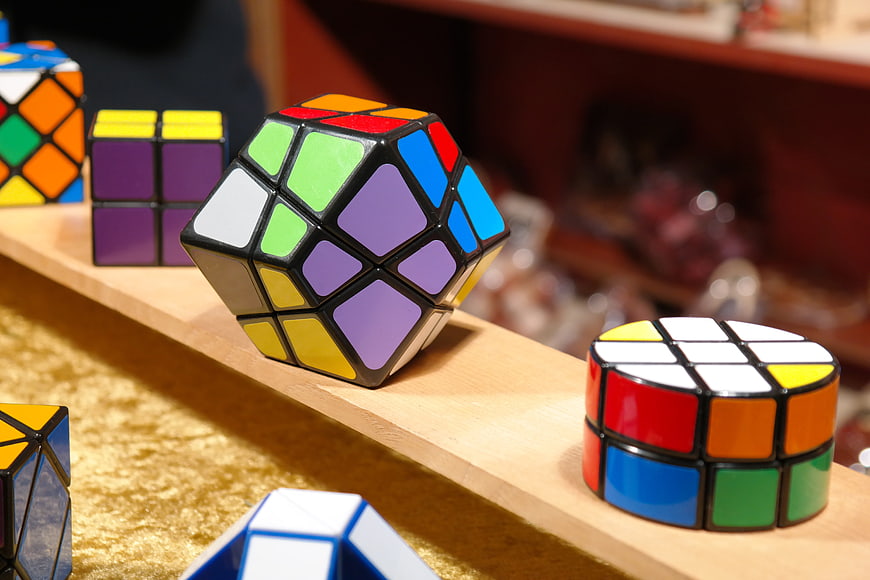Assorted Twisty Puzzle Cubes Displayed On Wooden Market Shelf