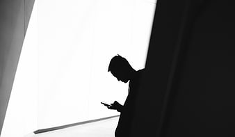 Silhouette of man texting on smartphone in high contrast black and white