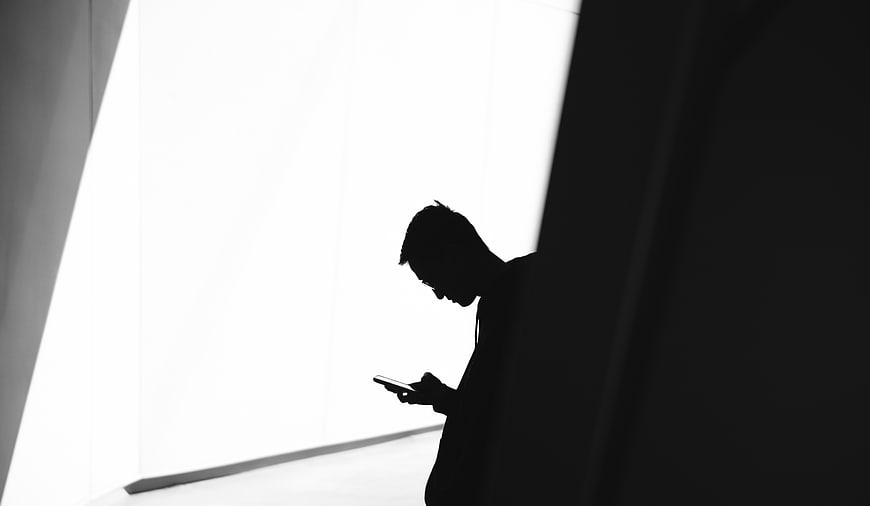 Silhouette of man texting on smartphone in high contrast black and white