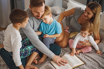 Family reading bedtime story together on bed