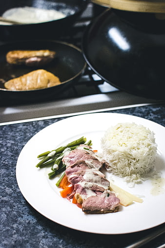 Plated duck breast with rice and green beans in kitchen