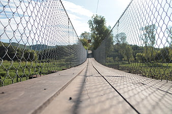 Low angle view of wooden suspension bridge with metal mesh