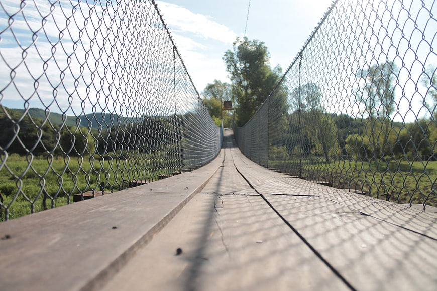Low angle view of wooden suspension bridge with metal mesh