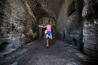 Woman stretching in ancient stone tunnel