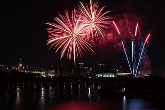 Red and white fireworks exploding over city skyline at night