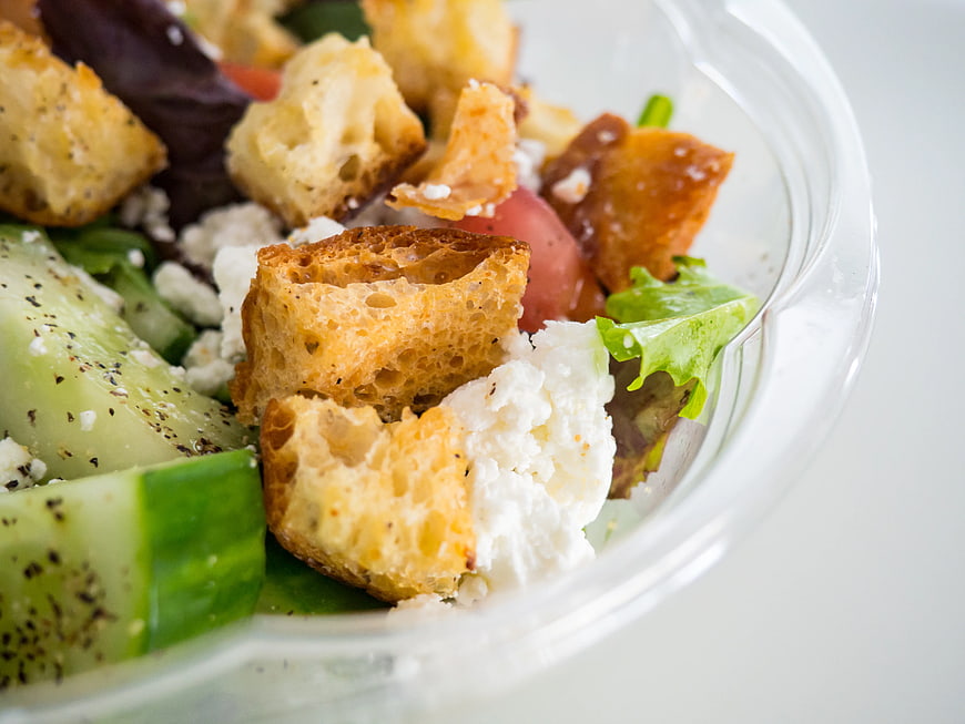 Close-up of fresh salad with croutons and feta cheese in plastic container