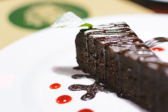 Close-up of rich chocolate cake with sauce drizzle on white plate