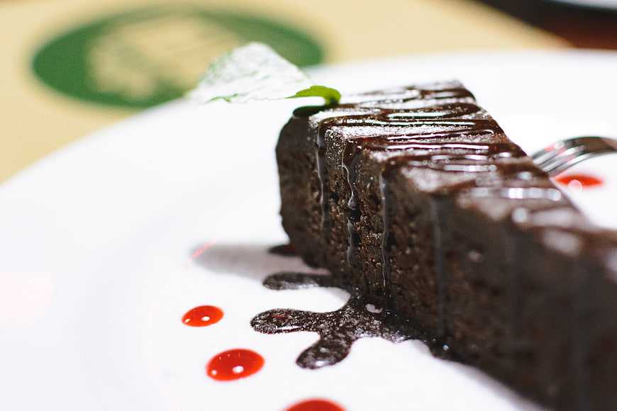 Close-up of rich chocolate cake with sauce drizzle on white plate