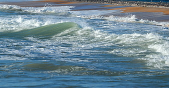 Ocean waves crashing on sandy beach with sea foam