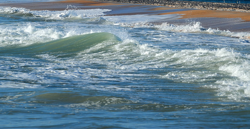 Ocean waves crashing on sandy beach with sea foam