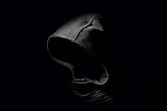 Mysterious black hooded figure in darkness