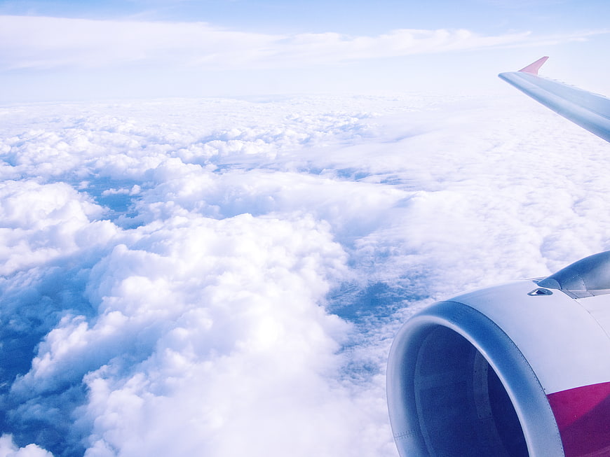 Airplane wing and engine view above clouds