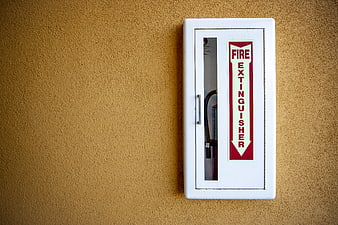 White Fire Extinguisher Cabinet on Textured Yellow Wall