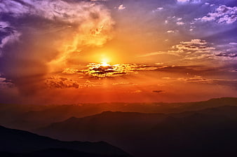 Dramatic Sunset Over Layered Mountain Silhouettes