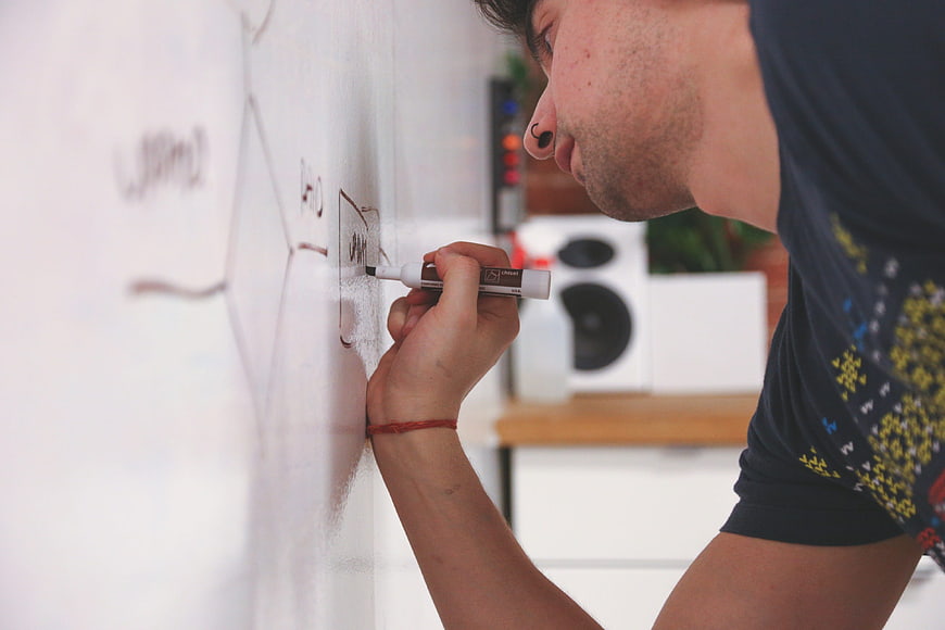 Man writing business strategy diagram on whiteboard in modern office