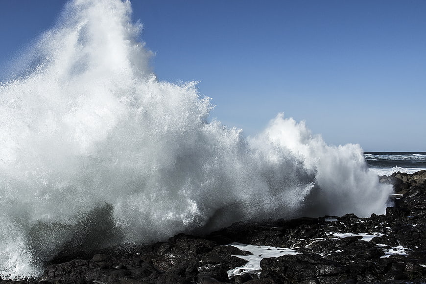 Powerful Ocean Wave Crashing Against Dark Volcanic Rocks