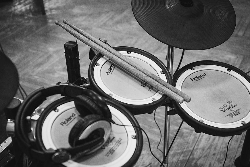 Black and white electronic drum kit with headphones and sticks