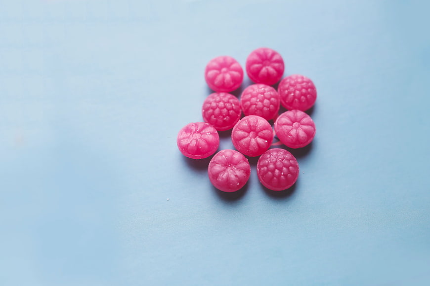 Pink fruit candies on light blue background