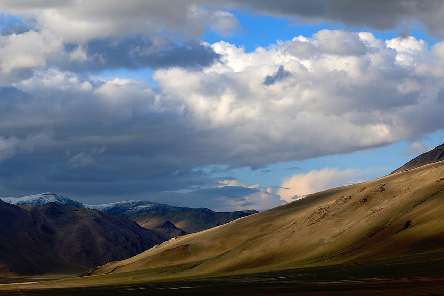 Dramatic mountain landscape with golden hills and cloudy sky