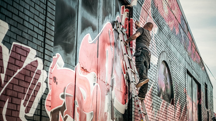 Graffiti Artist Painting Mural on Brick Wall
