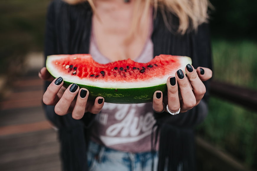 Woman holding fresh watermelon slice outdoors