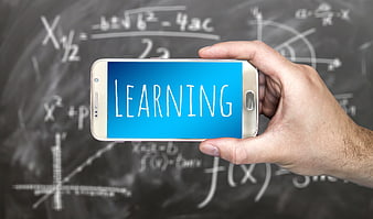 Hand holding smartphone displaying learning text against chalkboard math background