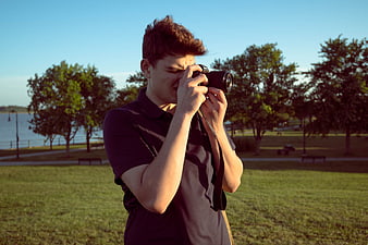 Young Man Taking Photo with Camera in Park