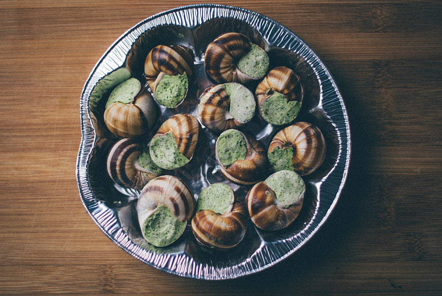 Top view of escargot in foil tray on wooden table