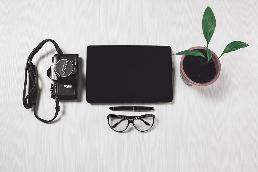Minimalist workspace with vintage camera, laptop, and plant