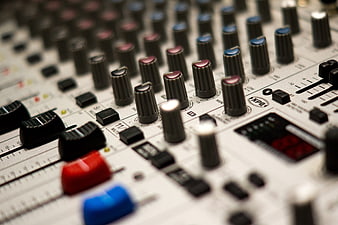 Close-up of professional audio mixing console with knobs and sliders