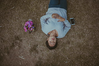 Top-down view of woman relaxing on grass with flowers