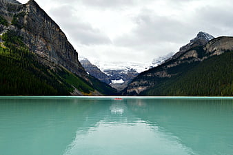 Turquoise glacial lake with canoe and snow-capped mountains