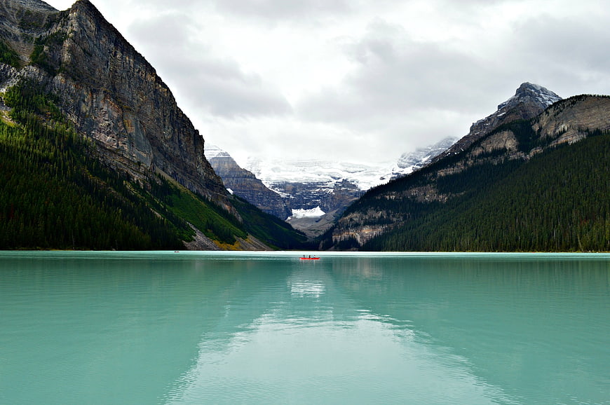 Turquoise glacial lake with canoe and snow-capped mountains
