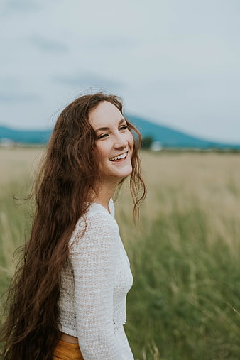 Happy Woman with Long Hair Smiling in Grassy Field