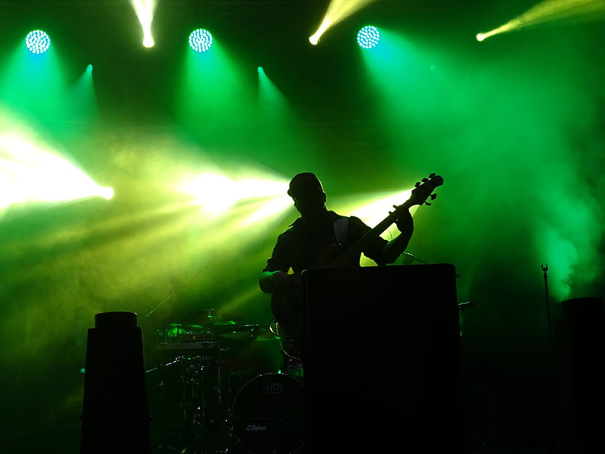 Silhouette of Guitarist Performing on Stage with Green Lights